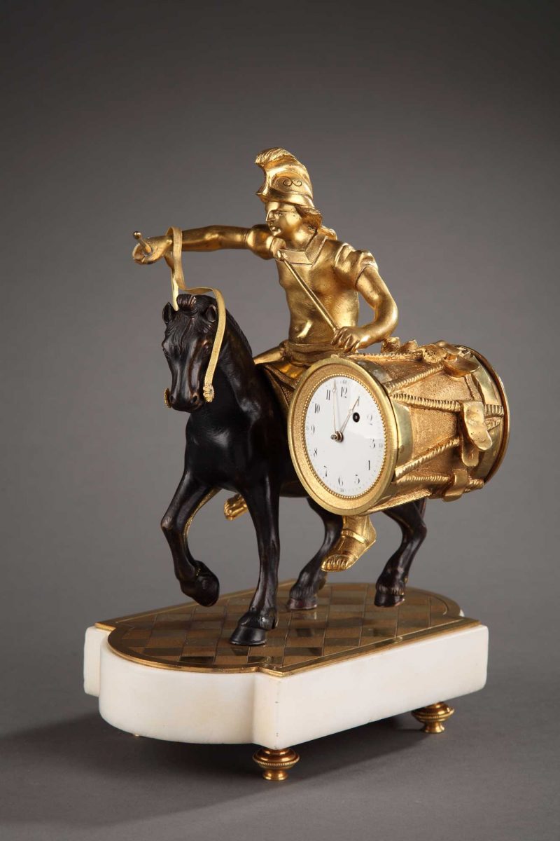 Pendulette d'époque Louis XVI en bronze doré ciselé et patiné. Mouvement de montre à coq. Base en marbre blanc sur 4 patins.
