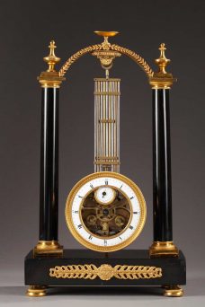 Pendule portique oscillante en marbre noir, bronze doré et ciselé. Suspension au couteau, mouvement dans la lentille du balancier avec cadran annulaire pour les heures et cadran secondaire pour les secondes.