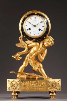 Pendule en bronze doré, ciselé et patine bleue d'époque Empire. Cupidon, dont le carquois et l'arc sont à ses pieds, maintient la voute céleste sur son épaule.
